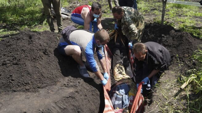 Exhumación de cadáveres cerca de Járkov Varias personas exhuman un cuerpo en la región de Járkov