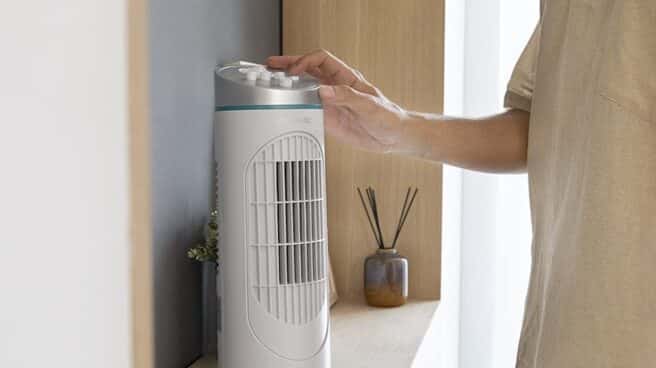 Los mejores ventiladores de Cecotec con descuento Chico poniendo en marcha un ventilador de torre de Cecotec
