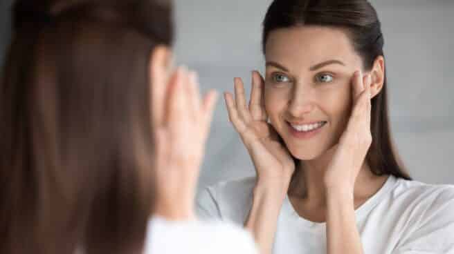 Mujer mirando la piel de su cara en un espejo