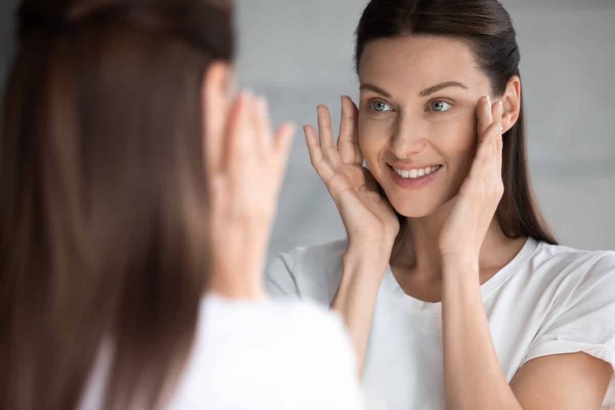 Mujer mirando la piel de su cara en un espejo