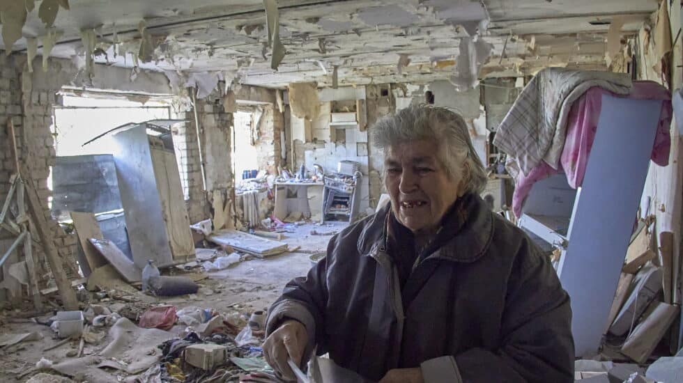 Una anciana muestra su casa dañada donde fue herido su hijo