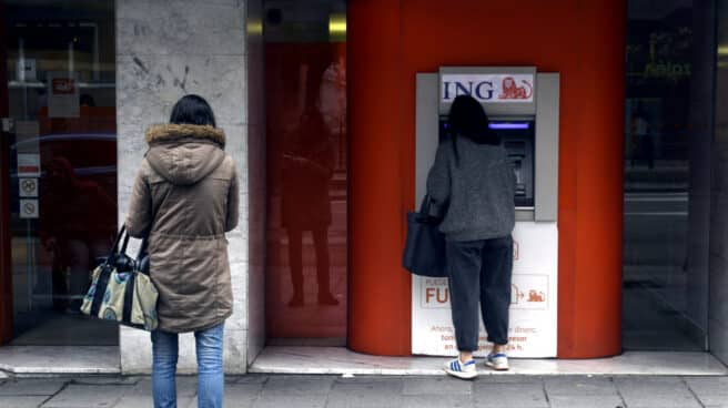 Una mujer espera su turno frente a un cajero de ING