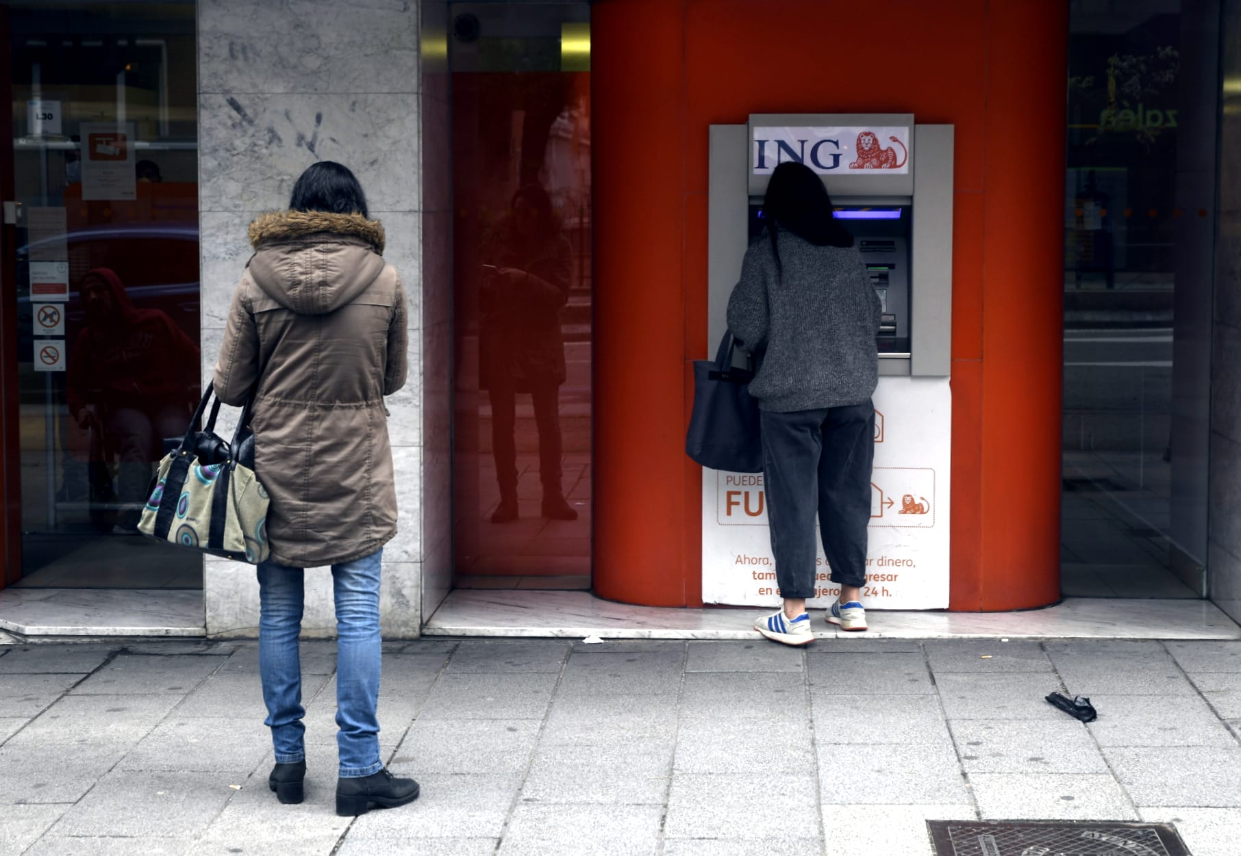 Una mujer espera su turno frente a un cajero de ING