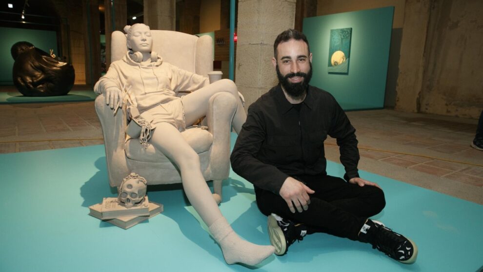 El artista Alejandro Monge posa con su obra 'El sueño de la razón produce monstruos' en la exposición "Lucha de Gigantes"
