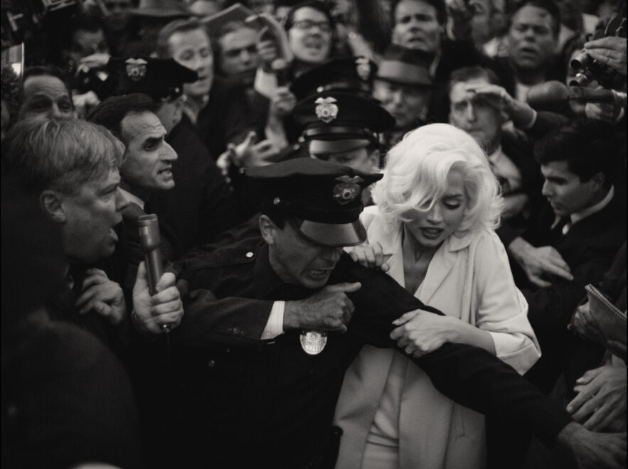 Escena de la película Blonde, sobre Marilyn Monroe, en la que se ve a la protagonista, Ana de Armas, rodeada de gente y periodistas.
