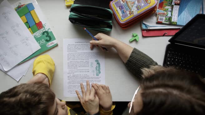 Un niño estudia y hace los deberes en casa con la ayuda de su madre