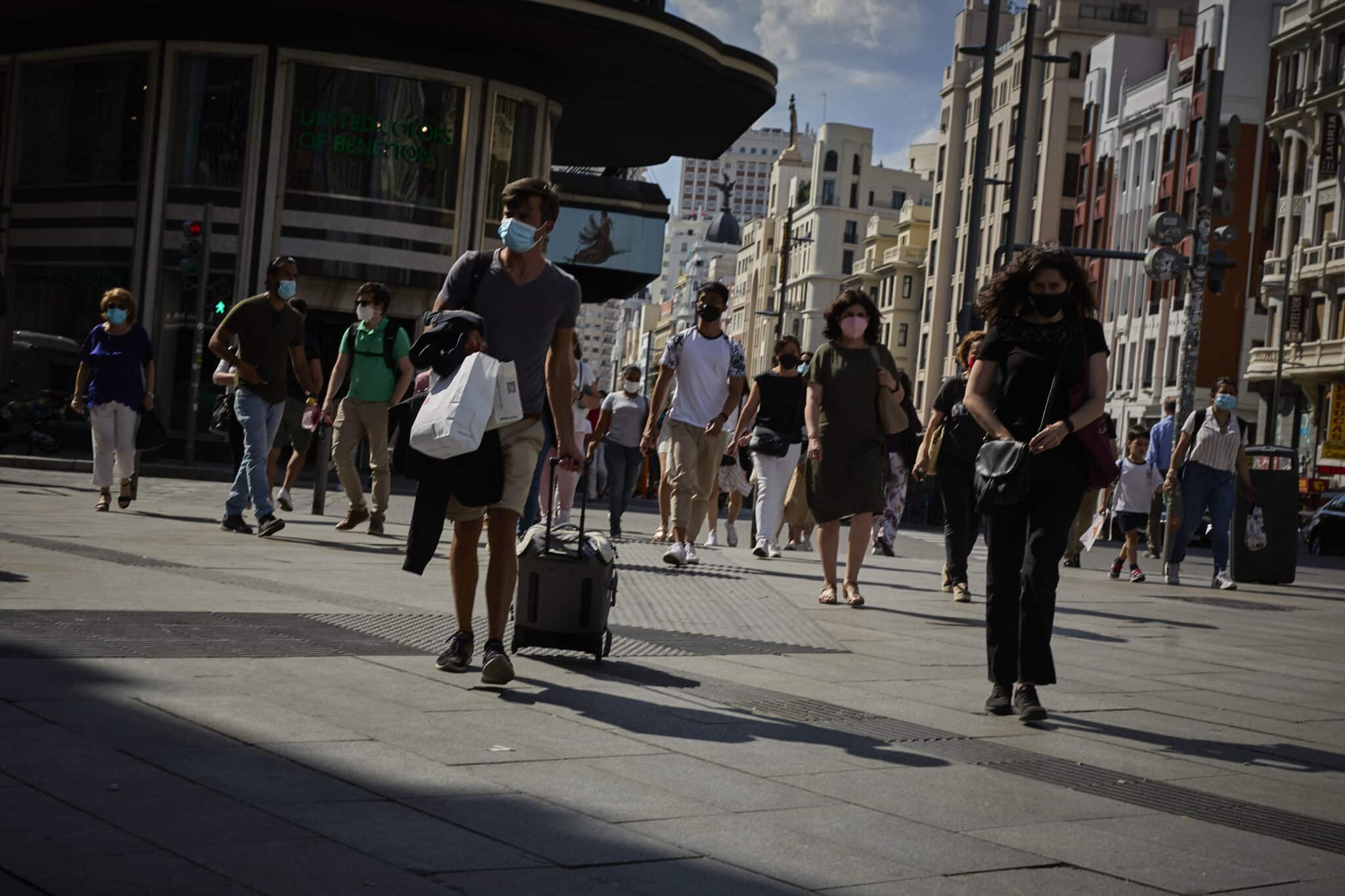 Un turista camina con una maleta por la Gran Vía de Madrid.