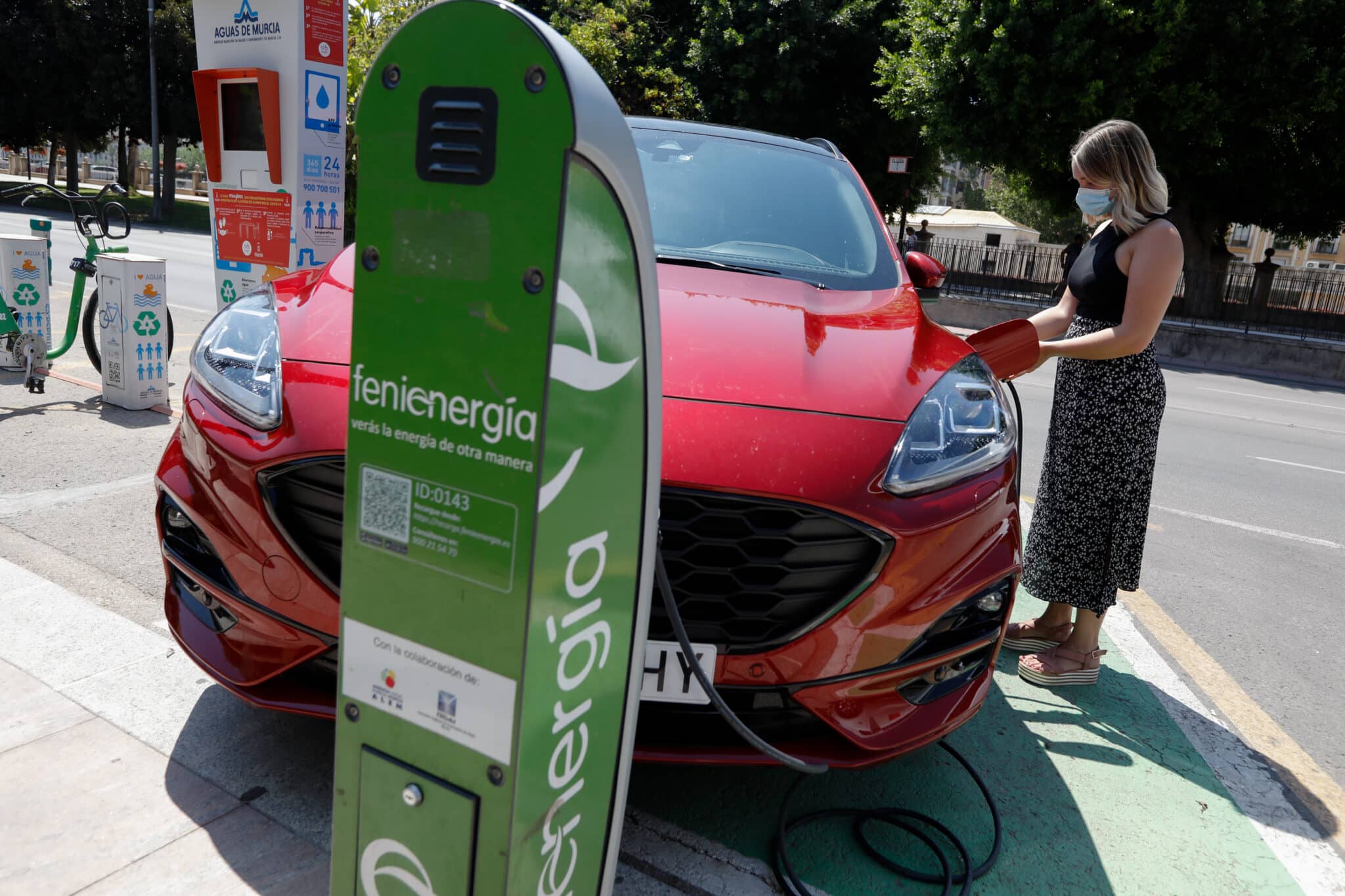 Una persona recarga un coche eléctrico en un punto de recarga