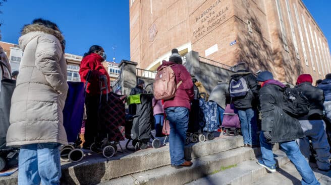 Varias personas hacen cola para recibir alimentos de la Fundación Madrina en Madrid.