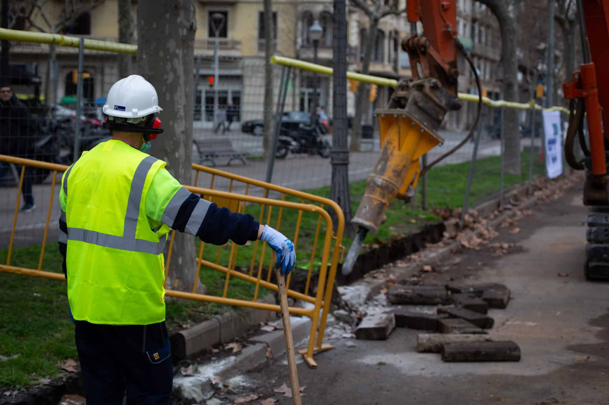 Un obrero y una máquina excavadora trabajan en las obras para unir el tranvía por la Diagonal (Barcelona).