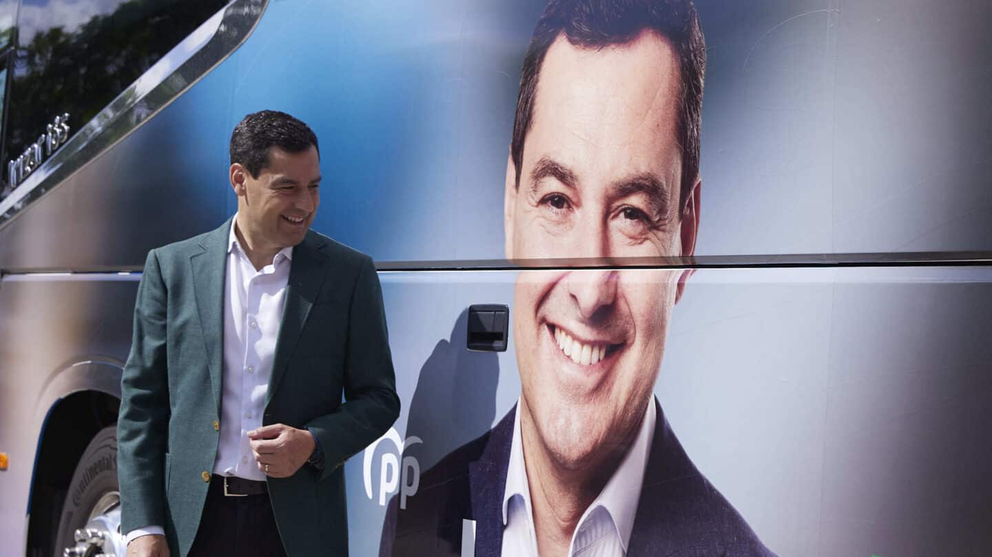 El candidato del Partido Popular a la presidencia de la Junta de Andalucía, Juanma Moreno, posa con el autobus de la caravana durante la atención a los medios en la puerta del Hospital Militar en Sevilla, a 3 de junio de 2022.