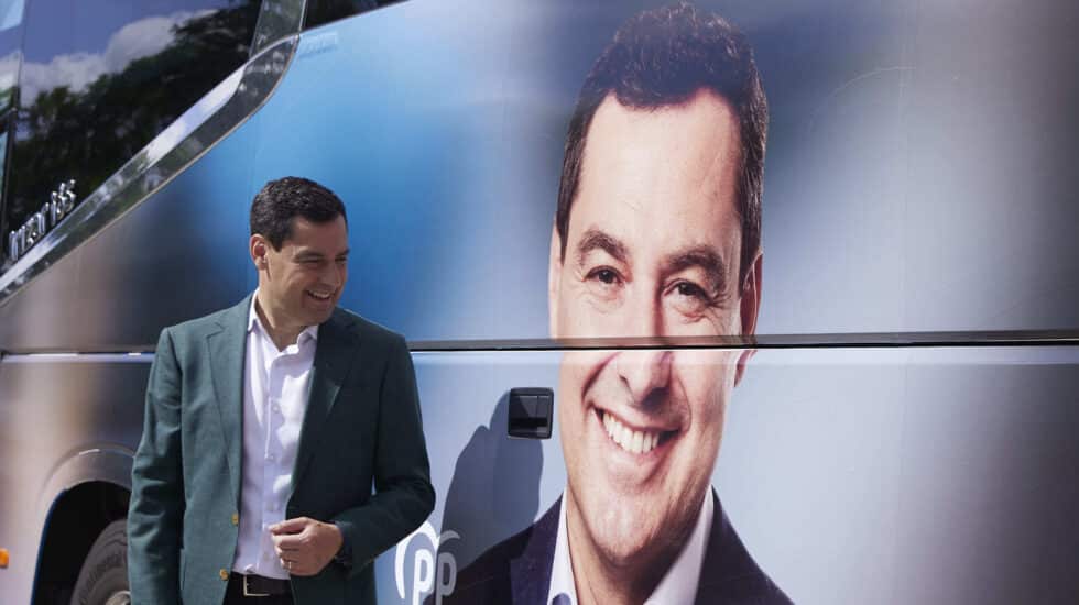 El candidato del Partido Popular a la presidencia de la Junta de Andalucía, Juanma Moreno, posa con el autobus de la caravana durante la atención a los medios en la puerta del Hospital Militar en Sevilla, a 3 de junio de 2022.