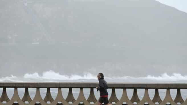 Un hombre, con chubasquero, corre por el Paseo Marítimo de La Coruña