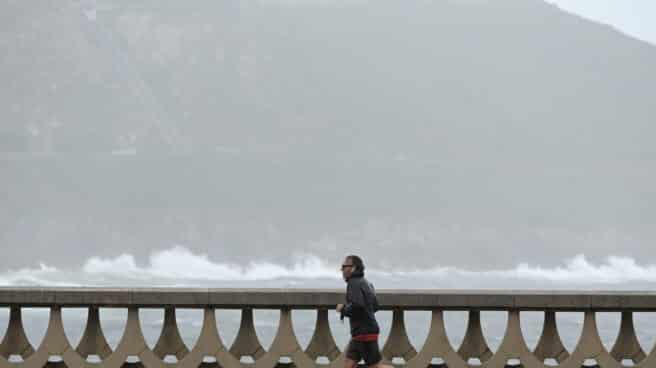 Las lluvias regarán este sábado el tercio norte y las tormentas afectarán a Pirineos Un hombre, con chubasquero, corre por el Paseo Marítimo de La Coruña