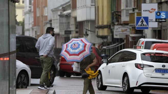 Una mujer se resguarda del viento y la lluvia con un paraguas en el centro de la ciudad