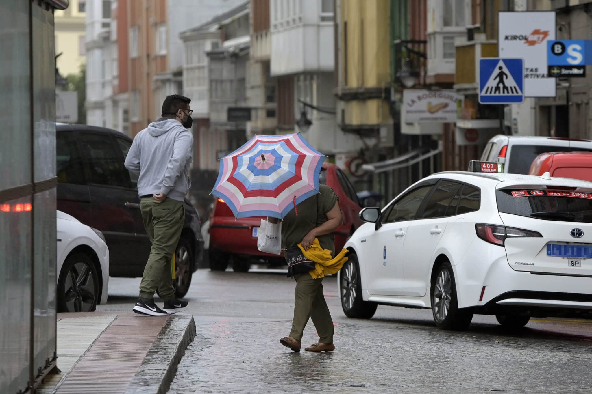 Una mujer se resguarda del viento y la lluvia con un paraguas en el centro de la ciudad