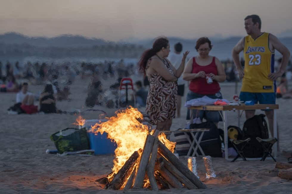 Varias personas frente a una hoguera en la playa de la Malvarrosa durante la Noche de San Juan