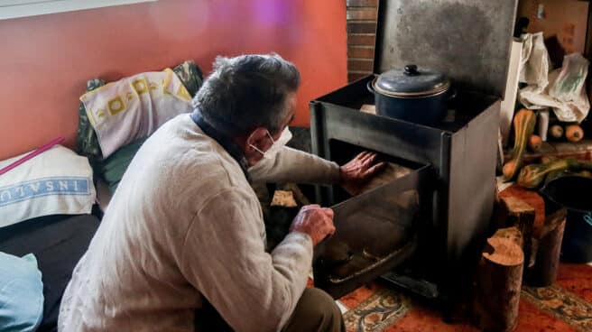 La Fundación Madrina dona alimentos en la Cañada Real Un hombre calienta una estufa en su vivienda de la Cañada Real, en Madrid.