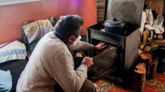 Un hombre calienta una estufa en su vivienda de la Cañada Real, en Madrid.