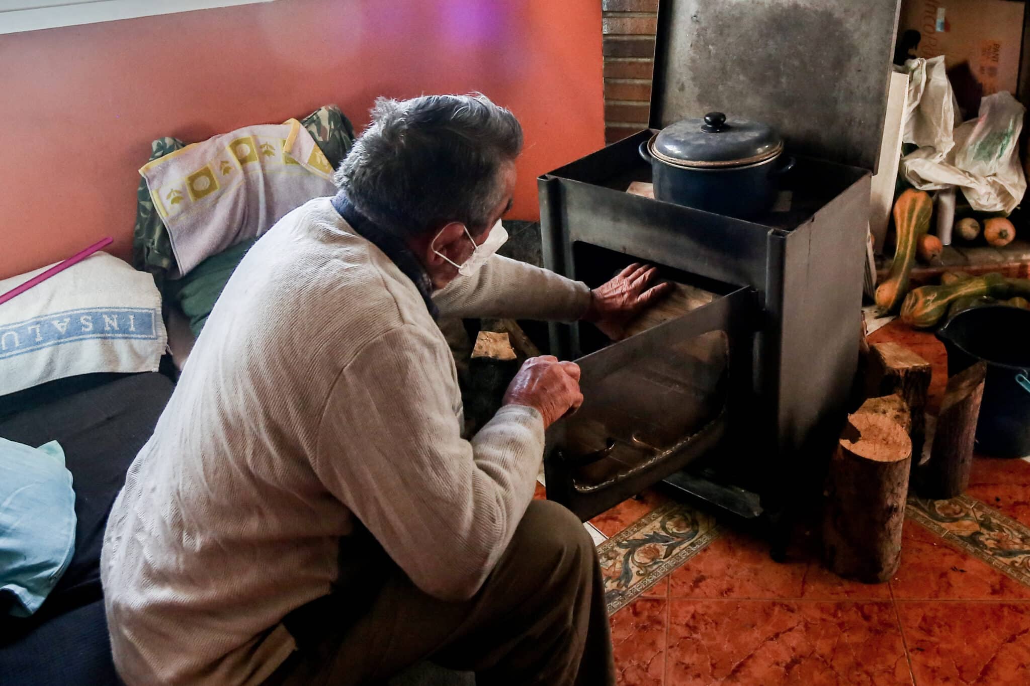 Un hombre calienta una estufa en su vivienda de la Cañada Real, en Madrid.