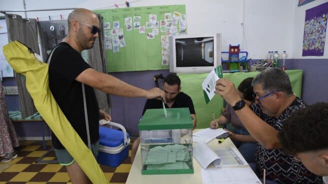 Un hombre cargado con nevera y sombrilla vota este domingo en Almería en las elecciones a la Junta de Andalucía.