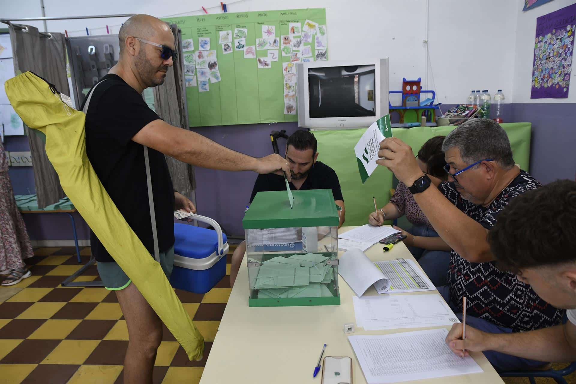 Un hombre cargado con nevera y sombrilla vota este domingo en Almería en las elecciones a la Junta de Andalucía.