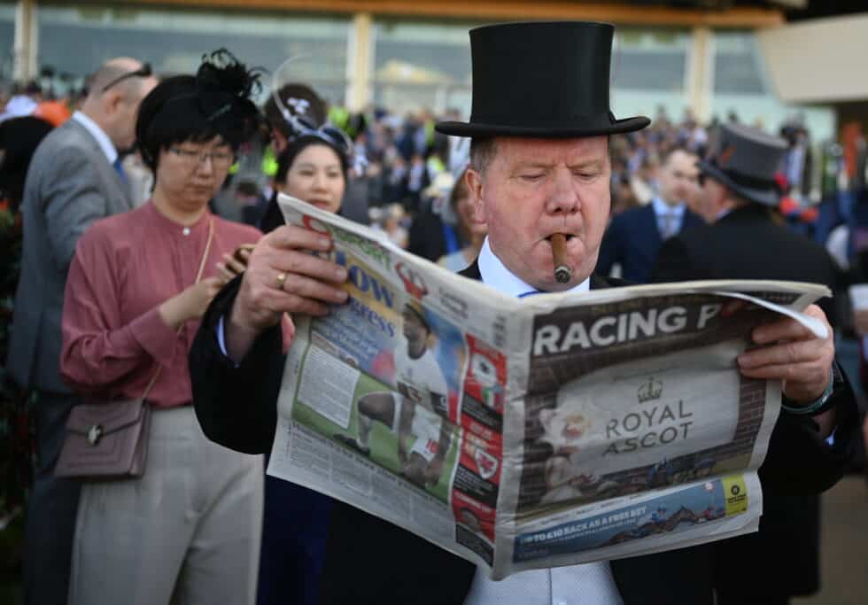 Un corredor fuma un cigarro y lee un periódico de carreras el primer día de Royal Ascot, en Ascot, Gran Bretaña