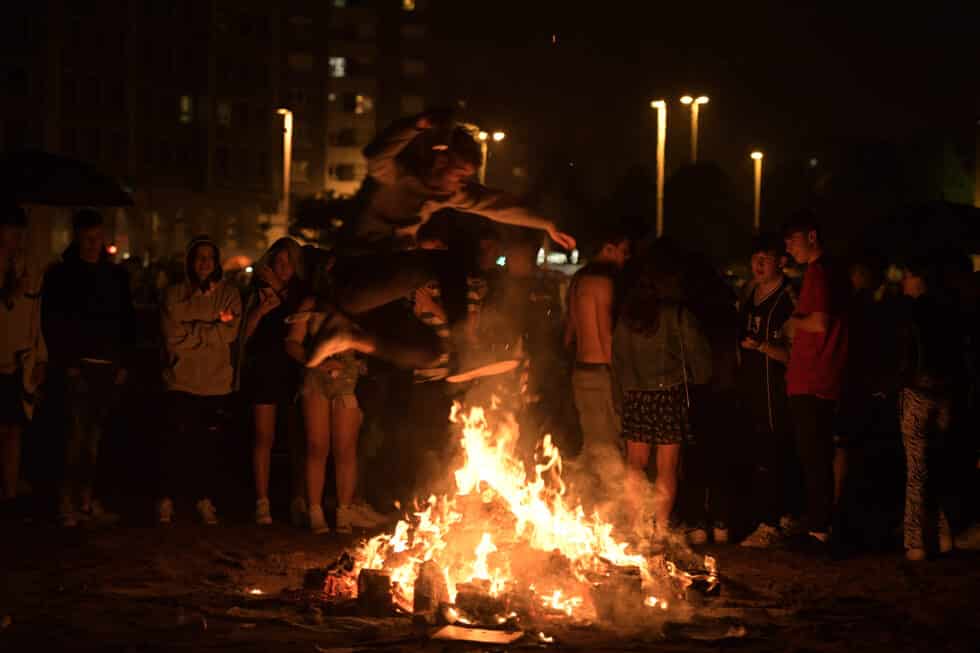 Cientos de gijoneses celebran junto a las hogueras la Noche de San Juan 2022 en la playa de Poniente, en Gijón.