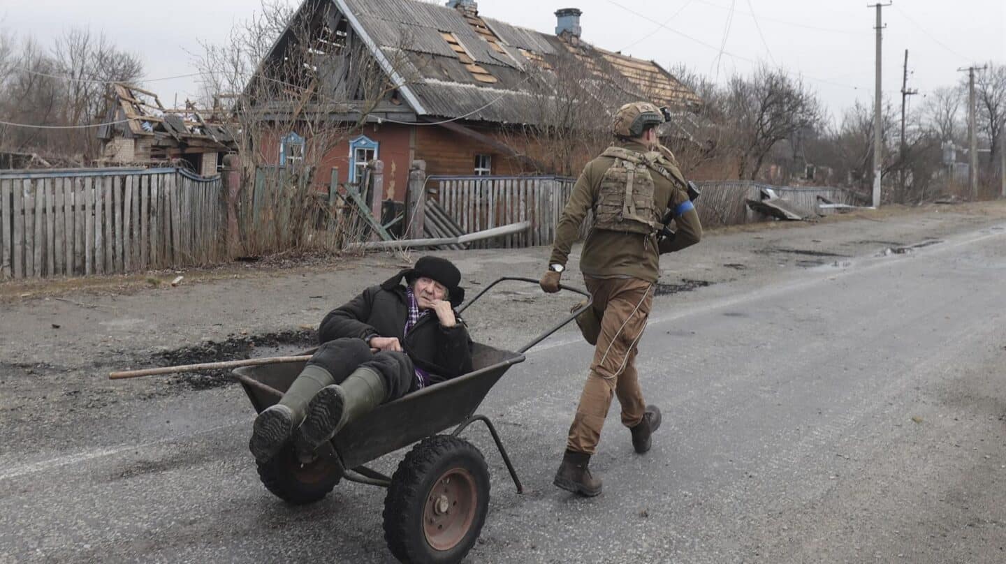 Un soldado ucraniano evacúa a un anciano de su hogar, destruido por las bombas, en Kiev