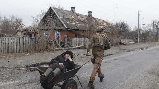 Un soldado ucraniano evacúa a un anciano de su hogar, destruido por las bombas, en Kiev