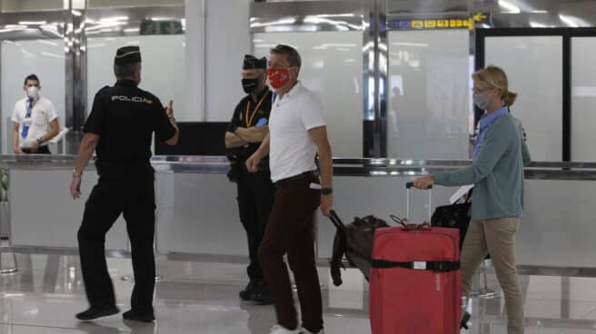 Imagen de archivo de dos viajeros que llegan al Aeropuerto de Palma de Mallorca junto a la Policía Nacional