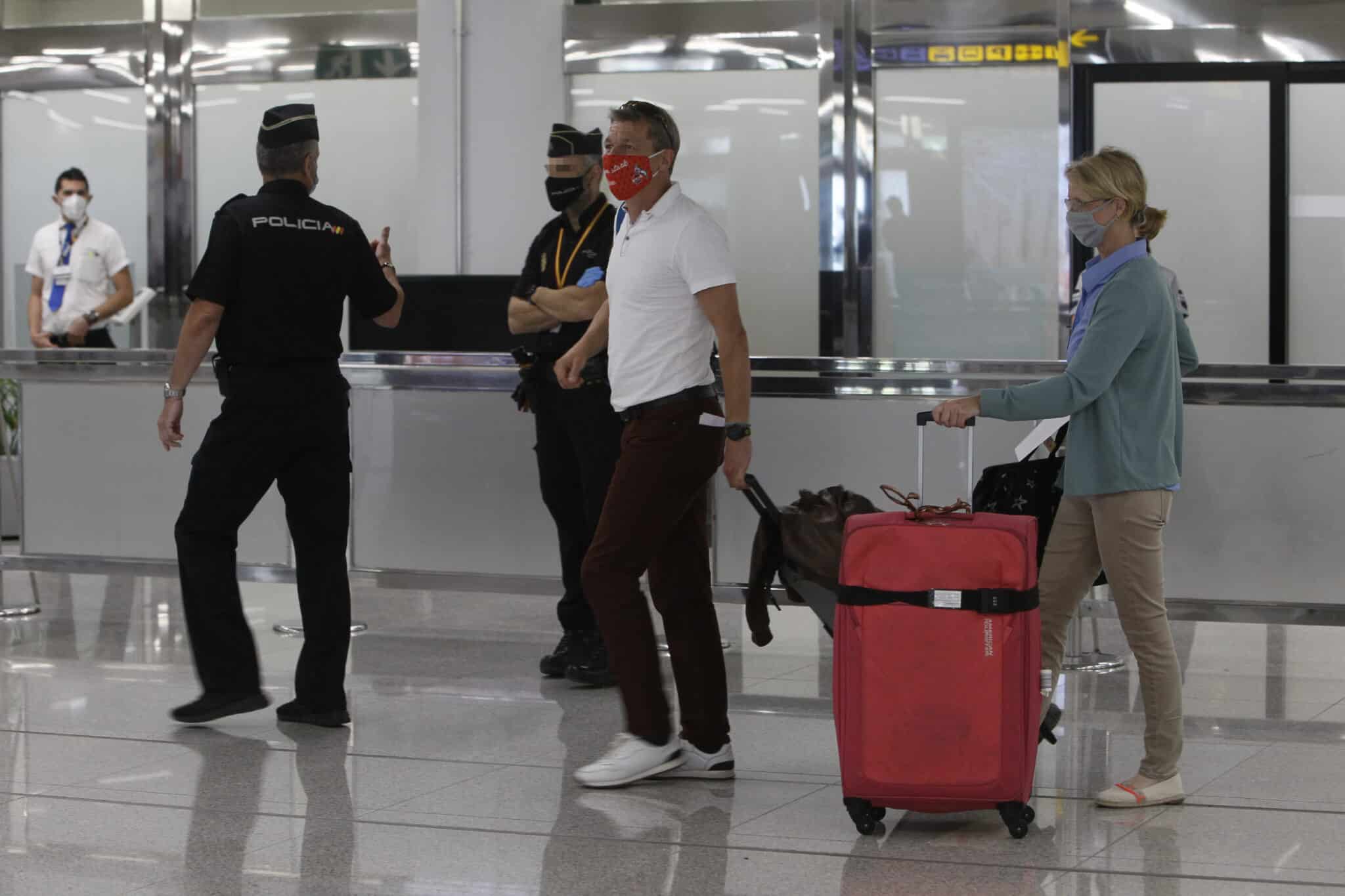 Imagen de archivo de dos viajeros que llegan al Aeropuerto de Palma de Mallorca junto a la Policía Nacional