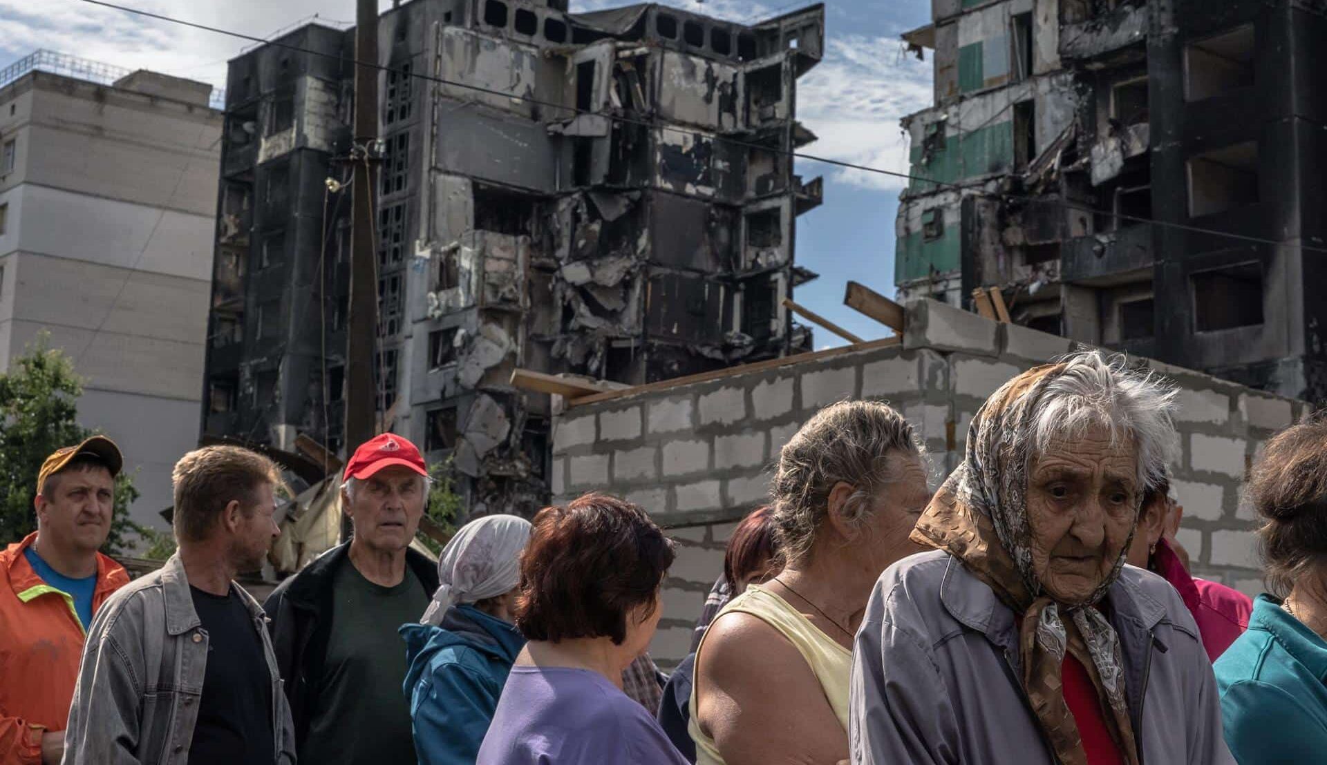 Residentes de Borodyanka al lado de un edificio bombardeado esperan a recibir ayuda humanitaria