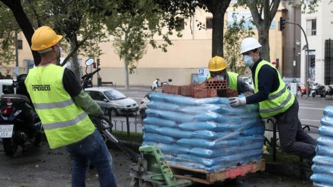 Varios obreros empujan material de construcción en Madrid.