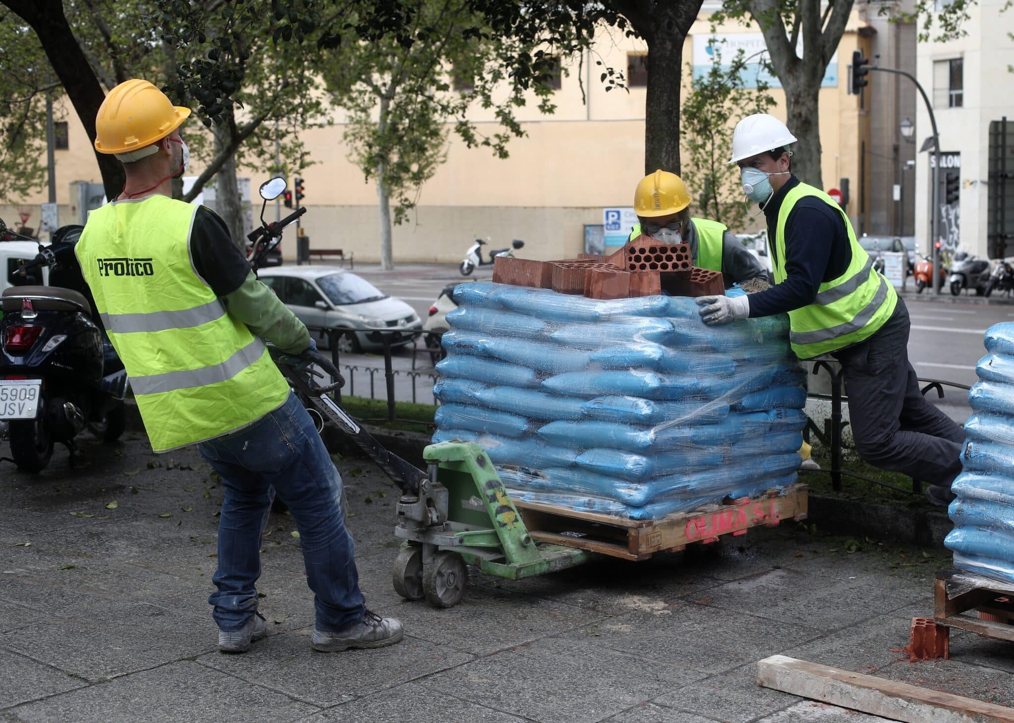 Varios obreros empujan material de construcción en Madrid.
