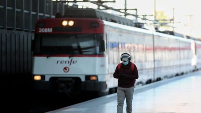 Un hombre camina por un andén frente a un tren de Cercanías de Renfe.