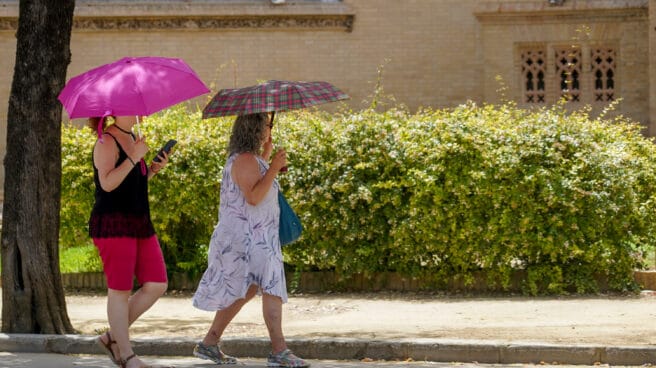 Dos mujeres con un paraguas pasean por el Parque de Maria Luisa en Sevilla Dos mujeres con un paraguas pasean por el Parque de Maria Luisa en Sevilla