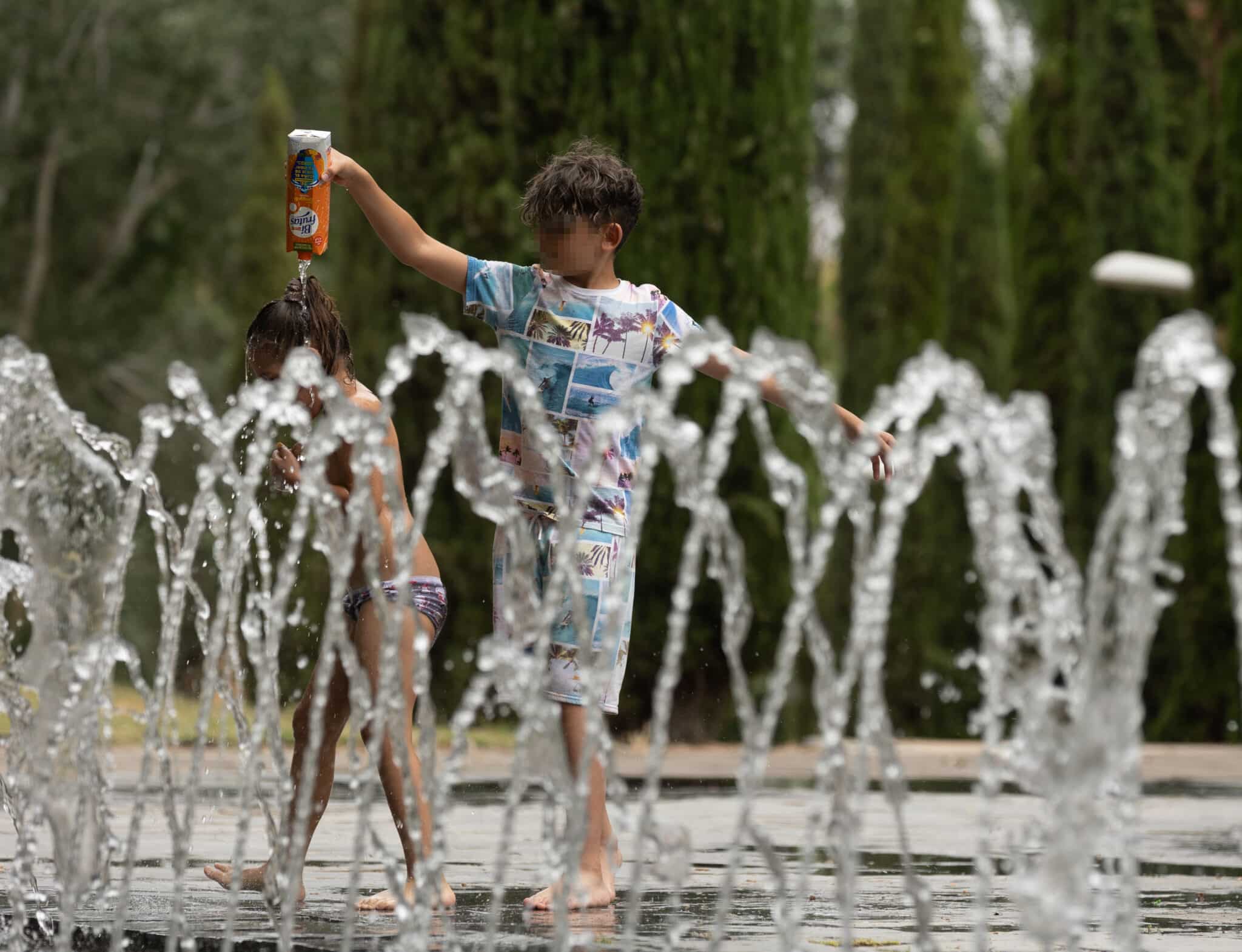 Dos niños se mojan entre ellos en los chorros de Madrid Río, a 16 de junio de 2022