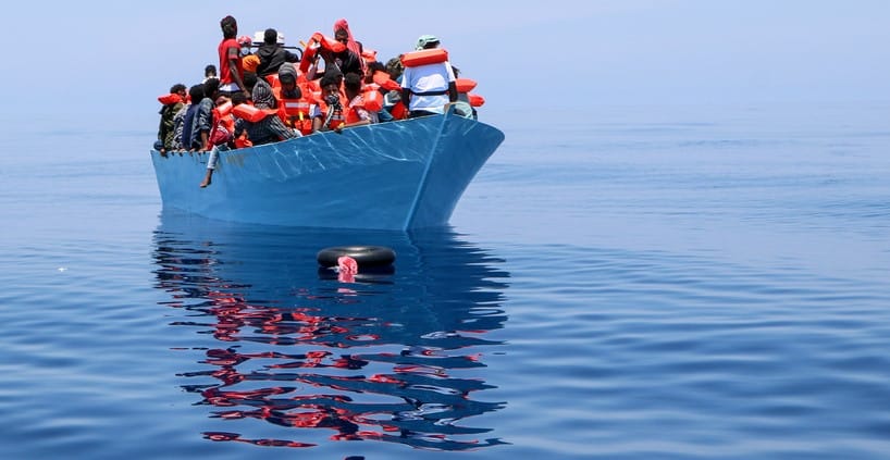 Una embarcación con numerosos inmigrantes a bordo, navegando por el Mediterráneo central.