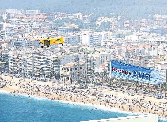 Avioneta con publicidad en la playa.