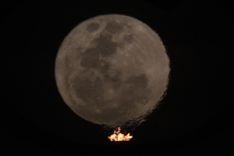 Fotografía de la superluna del ciervo a través del fuego que se enciende en el Panteón de la Patria y la Libertad, hoy en Brasilia (Brasil).