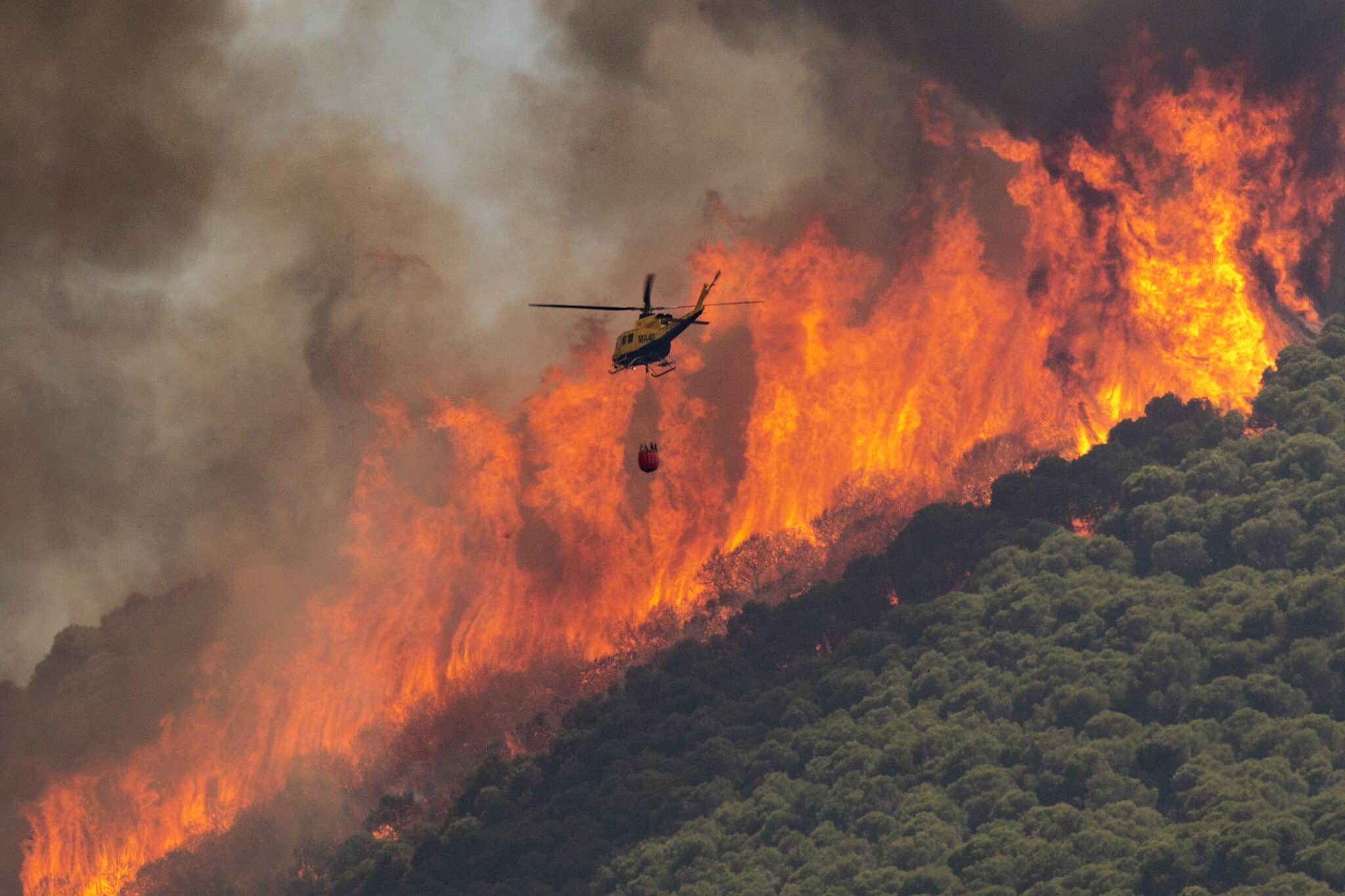 Un helicóptero trabaja en las tareas de extinción del incendio declarado en el paraje El Higuerón de Mijas (Málaga).