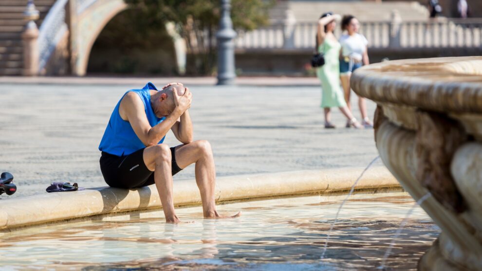 Hombre teniendo un golpe de calor en una fuente en Sevilla, España