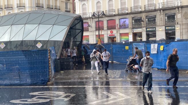 Ciudadanos a la carrera tras salir de la estación de Sol en plena tormenta en Madrid.