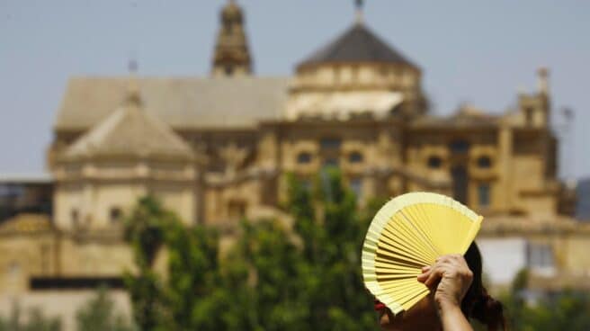 Una persona pasea por la mezquita de Córdoba tapada con un abanico.