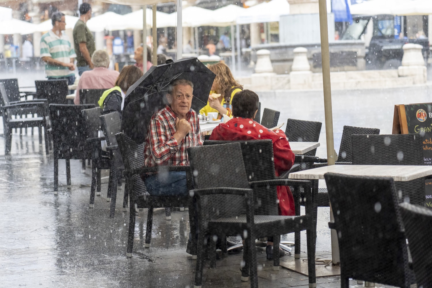 Un hombre se protege de la lluvia con su paraguas este miércoles en una terraza de Teruel en la Plaza del Torico.