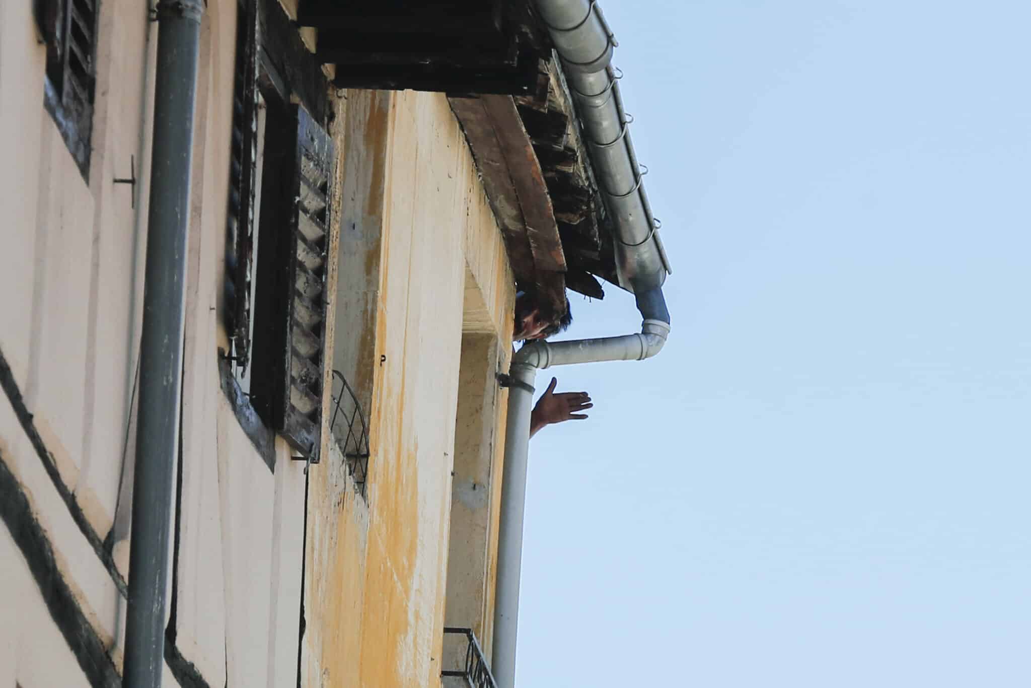 El hombre (c) que se ha atrincherado en su piso en el Casco Viejo de Vitoria saca la cabeza por la ventana mientras que la Ertzaintza ha desalojado el edificio por precaución