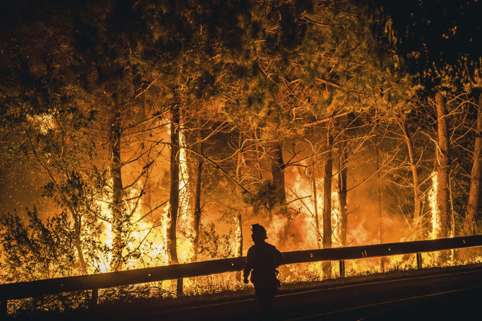 Un operario de las Brigadas de Refuerzo de Incendios Forestales (BRIF) lucha contra las llamas en la madrugada de este sábado para extinguir el incendio declarado en el día anterior en la parroquia de Cures, Boiro, A Coruña