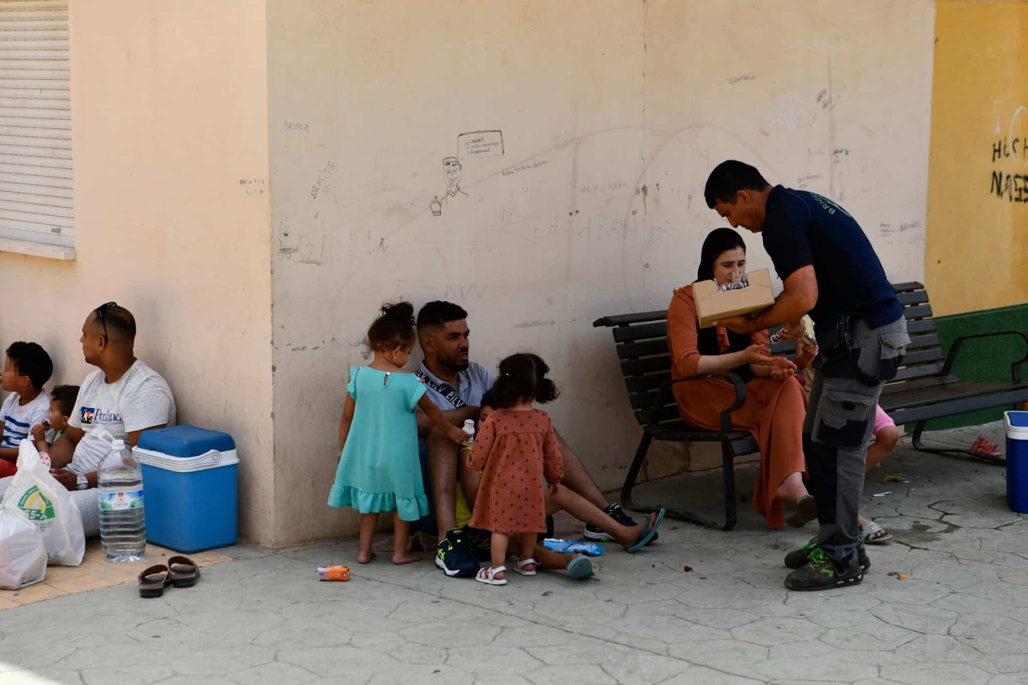 Varias personas reciben agua y alimento en la zona de embolsamiento de Loma Colmenar para pasar por la frontera del Tarajal, de Ceuta a Marruecos