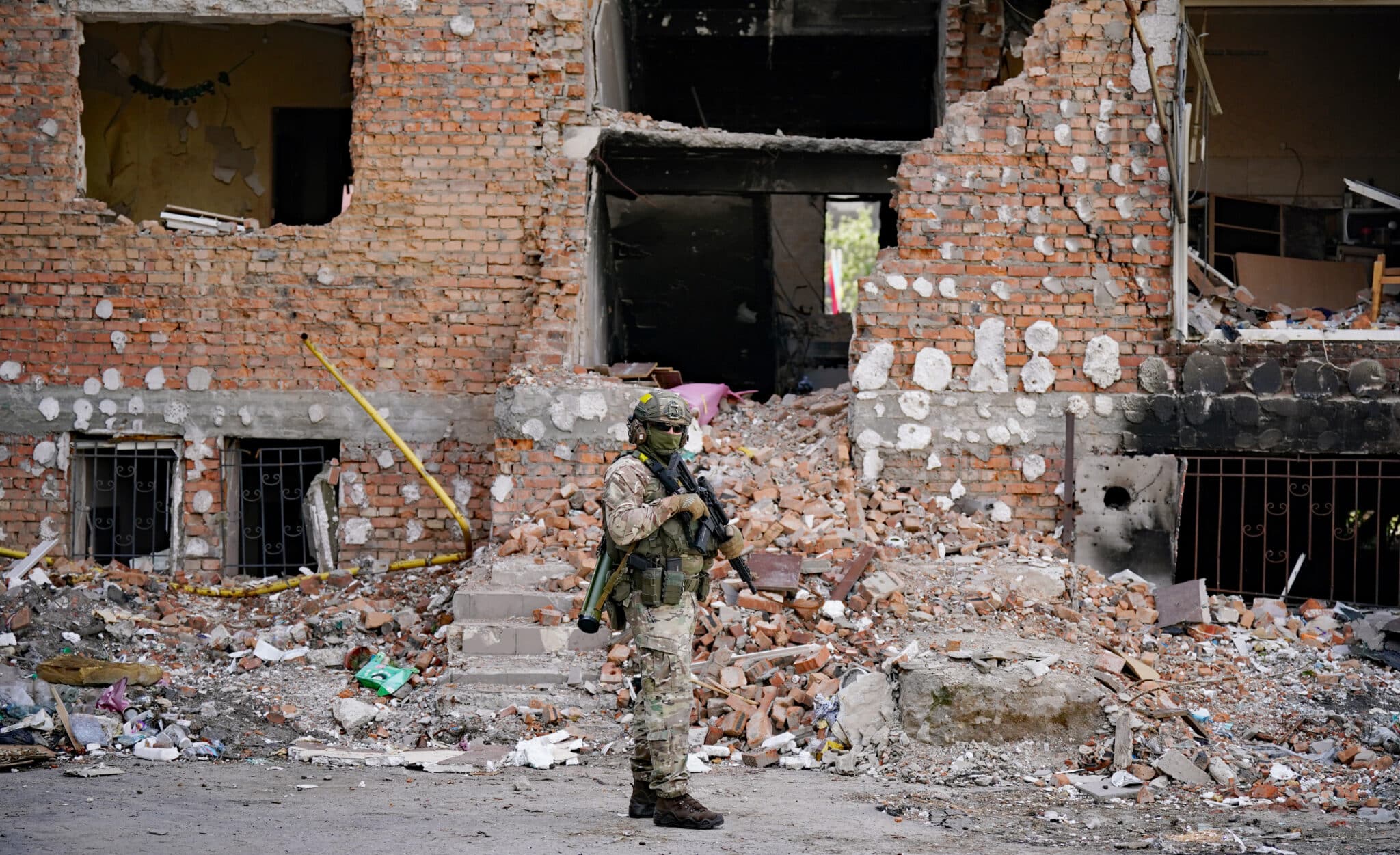 Ucrania, Irpin: Un soldado ucraniano se para con su rifle frente a un edificio destruido.